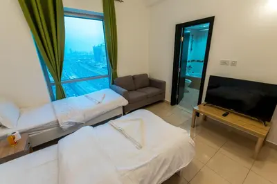 a room with a bed and a couch and a tv at La Rivera Rooms for Ladies in Dubai
