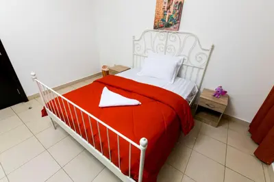 a white bed with red sheets and white pillows at La Rivera Rooms for Ladies in Dubai