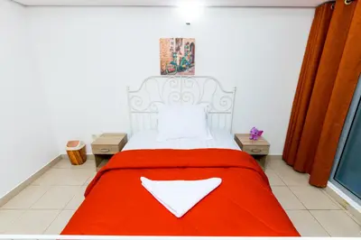 a bedroom with a bed with a red blanket at La Rivera Rooms for Ladies in Dubai