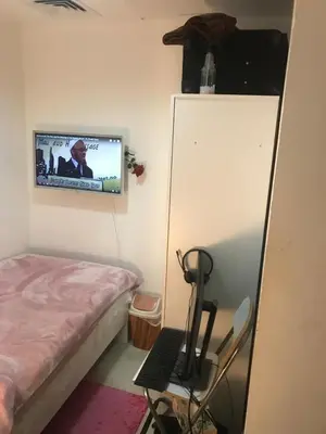 a bedroom with a bed and a tv on the wall at La Rivera Rooms for Ladies in Dubai