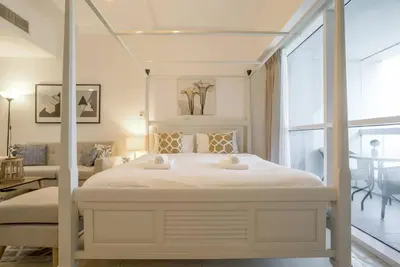 a white bedroom with a bed and a living room at GuestReady - Modern Studio | Stunning Marina Views in Dubai