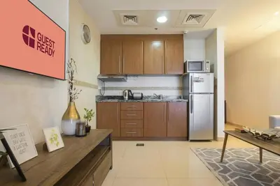 a kitchen with wooden cabinets and a refrigerator at GuestReady - Modern Studio | Stunning Marina Views in Dubai