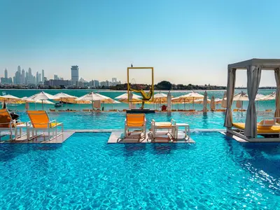a pool with chairs and a swing in the water at C Central Hotel and Resort The Palm in Dubai