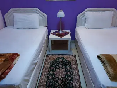 two beds in a room with a table with a lamp at Al Jazeera Hotel Apartments LLC in Dubai