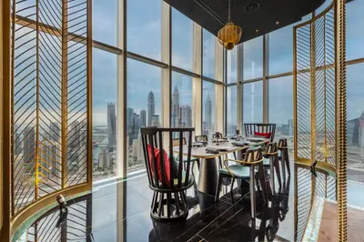 a dining room with a table and chairs in front of a window at Taj Jumeirah Lakes Towers in Dubai