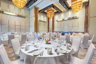 a banquet hall with white tables and chairs and chandeliers at Taj Jumeirah Lakes Towers in Dubai