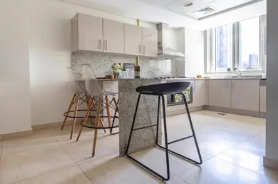 a kitchen with white cabinets and a counter with stools at Frank Porter - Mon Reve in Dubai