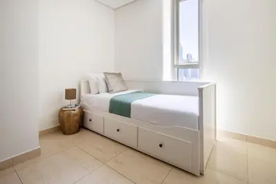 a white bedroom with a bed and a window at Frank Porter - Mon Reve in Dubai