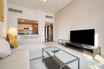 a living room with a white couch and a flat screen tv at Sophisticated One Bedroom with Full Marina View in Dubai
