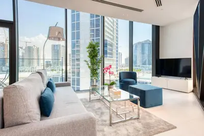 a living room with a couch and a tv and large windows at Maison Privee - Luxury, Spacious, Modern Near Burj Khalifa and Dubai Canal in Dubai