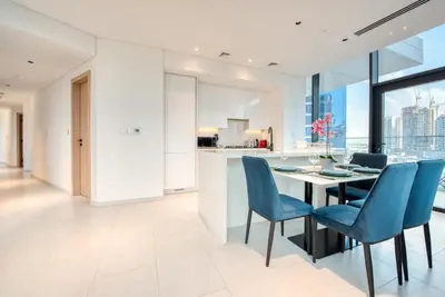a kitchen and dining room with a table and blue chairs at Maison Privee - Luxury, Spacious, Modern Near Burj Khalifa and Dubai Canal in Dubai