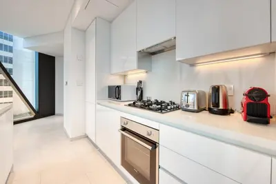 a kitchen with white cabinets and a stove top oven at Maison Privee - Luxury, Spacious, Modern Near Burj Khalifa and Dubai Canal in Dubai