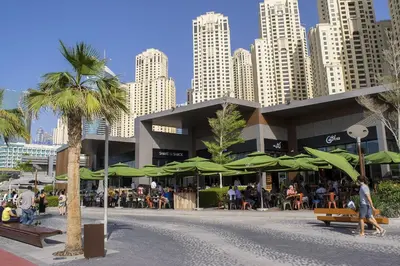 a building with green umbrellas in front of a city at Silverene Towers Dubai Marina - By Home Of Choice in Dubai