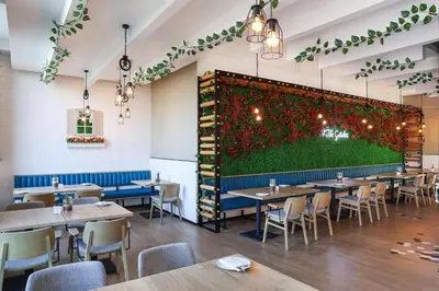 a restaurant with tables and a green wall at JA The Manor Hotel, Dubai in Dubai