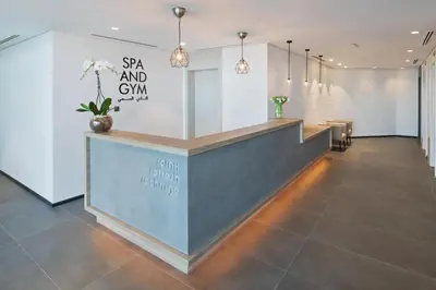 a hotel lobby with a reception desk and pendant lights at JA The Manor Hotel, Dubai in Dubai