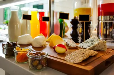 a cutting board with cheese and other foods on a counter at Lemon Tree Hotel, Jumeirah Dubai in Dubai