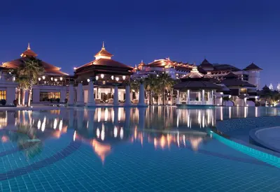 a large building with a swimming pool at night at Anantara The Palm Dubai Resort in Dubai