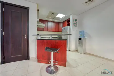 a kitchen with a stool in front of a door at Community Vibe Living with Wellness Access Close to Metro, Mediterranean, Discovery Gardens by Deluxe Holiday Homes in Dubai