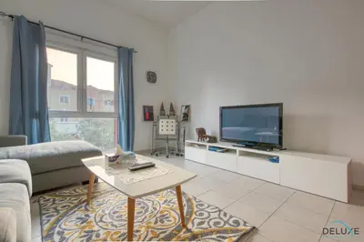 a living room with a couch and a tv at Community Vibe Living with Wellness Access Close to Metro, Mediterranean, Discovery Gardens by Deluxe Holiday Homes in Dubai