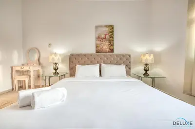 a bedroom with a large white bed with two tables at Community Vibe Living with Wellness Access Close to Metro, Mediterranean, Discovery Gardens by Deluxe Holiday Homes in Dubai