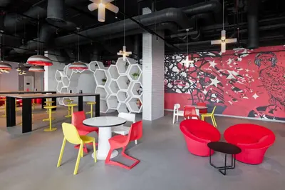 a room with colorful chairs and tables and a wall at Radisson RED Dubai Silicon Oasis in Dubai