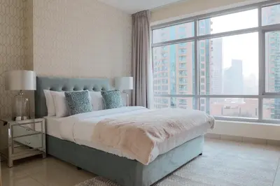 a bedroom with a bed and a large window at Nasma Luxury Stays - Pastel-Colored Apt With Jaw-Dropping Marina Views in Dubai