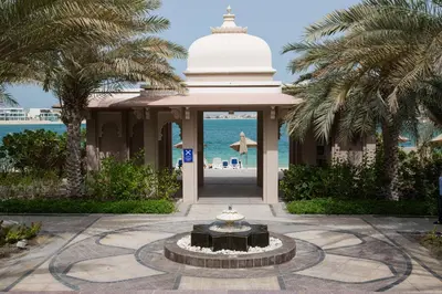 a building with a fountain in front of the ocean at HiGuests - Luxurious 1BR in Palms with Private Beach Access in Dubai