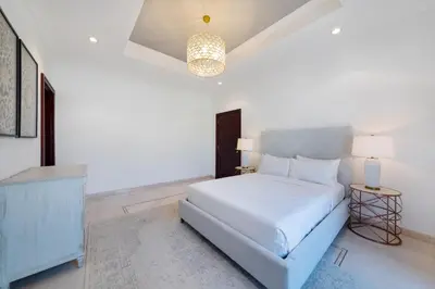 a white bedroom with a bed and a chandelier at Maison Privee - 5 Stars Villa with Private Pool or Beach on Palm Jumeirah in Dubai
