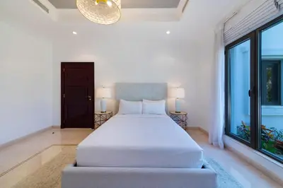 a white bedroom with a bed and large windows at Maison Privee - 5 Stars Villa with Private Pool or Beach on Palm Jumeirah in Dubai
