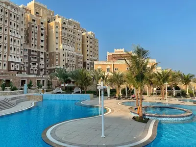 a large swimming pool with palm trees and buildings at Luxury Apartments at Balqis Residence in Dubai