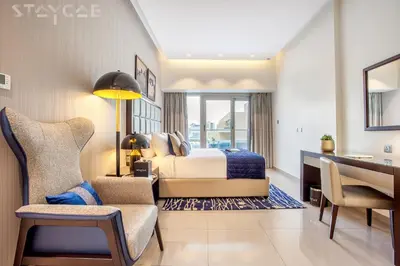 a bedroom with a bed and a desk and a chair at Staycae Holiday Homes - Majestine in Dubai
