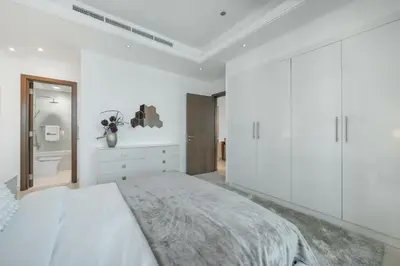 a white bedroom with a large bed and a bathroom at HiGuests - Spacious 1BR in Dubai Marina With Amazing Views in Dubai