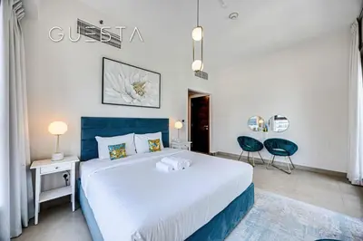 a bedroom with a large bed and two blue chairs at Sparkle Tower, Dubai Marina in Dubai