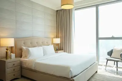 a bedroom with a large white bed and a chair at Westminster Boulevard Point in Dubai