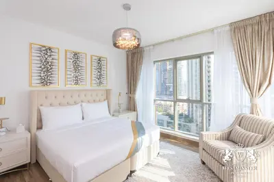 a bedroom with a bed and a chair and a window at Westminster Boulevard Central - Burj Khalifa in Dubai