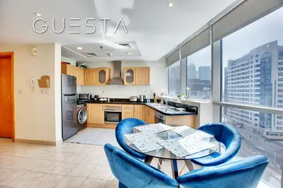 a kitchen with a glass table and blue chairs at The Waves by DAMAC, Dubai Marina in Dubai