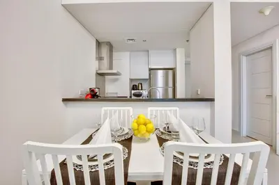 a white kitchen with a dining table and chairs at Ultra modern 1BD in Damac Heights Marina in Dubai