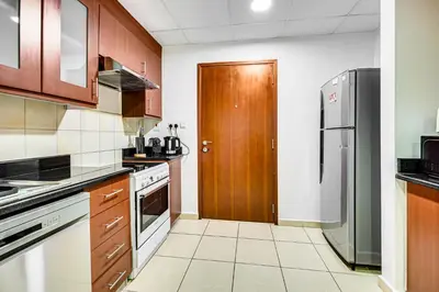 a kitchen with wooden cabinets and a refrigerator at Wonderful 2BD apartment near The Beach Sadaf JBR in Dubai