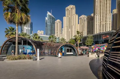a woman walking in front of a city with tall buildings at Wonderful 2BD apartment near The Beach Sadaf JBR in Dubai