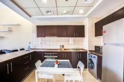 a kitchen with a white table and a white refrigerator at Bay Central 1BD apartment with awesome Marina view in Dubai