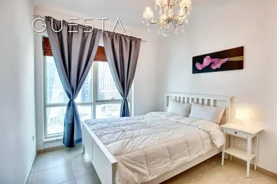 a bedroom with a bed and a window with a chandelier at Al Majara, Tower 1, Dubai Marina in Dubai