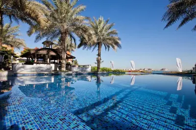 a swimming pool with palm trees in the background at Club Vista Mare, free Riva beach club access in Dubai
