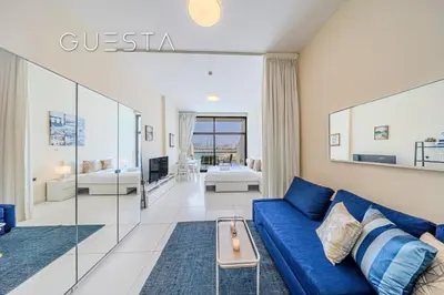 a living room with a blue couch and a table at Club Vista Mare, free Riva beach club access in Dubai