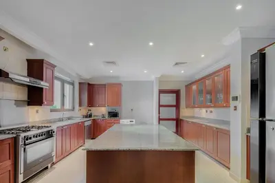 a large kitchen with wooden cabinets and granite counter tops at Maison Privee - Prvt Pool & Beach Access in Luxury Palm Jumeirah 6BR Villa in Dubai