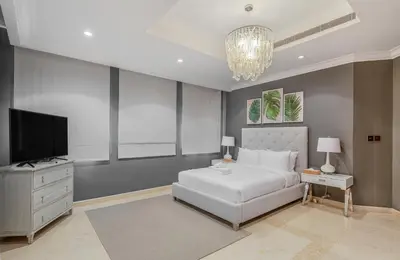 a bedroom with a white bed and a television at Maison Privee - Prvt Pool & Beach Access in Luxury Palm Jumeirah 6BR Villa in Dubai