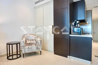 a living room with a chair and a kitchen at Staycae Holiday Homes - Upper Crest in Dubai