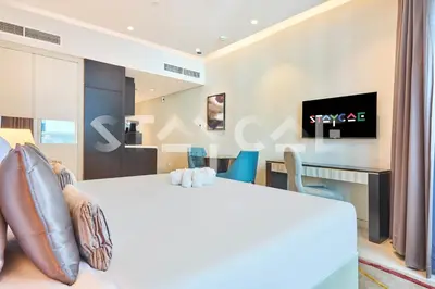 a hotel room with a bed and a table and a tv at Staycae Holiday Homes - Upper Crest in Dubai