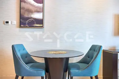 a table and two blue chairs in a room at Staycae Holiday Homes - Upper Crest in Dubai