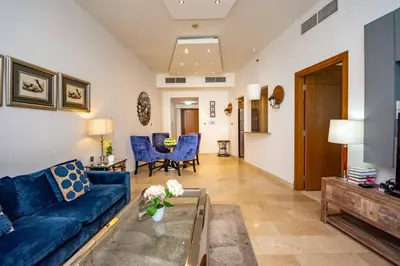 a living room with a blue couch and blue chairs at Stylish and Sleek 1 Bed + Study near the JBR beach in Dubai