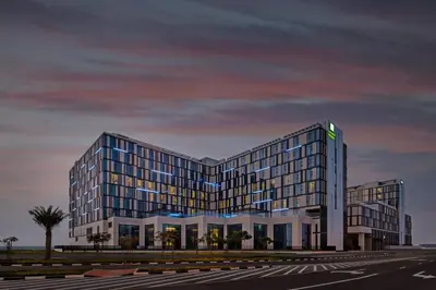 a rendering of a large building with a sunset at Staybridge Suites Dubai Al-Maktoum Airport by IHG in Dubai